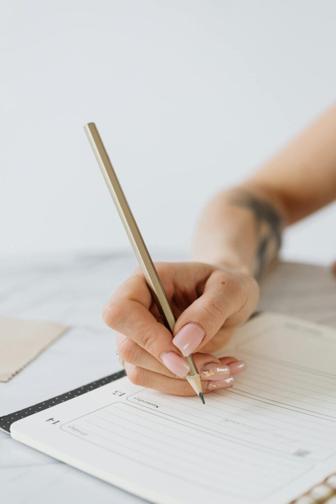 Personne qui écrit à l'aide d'un crayon à la mine dans un agenda.