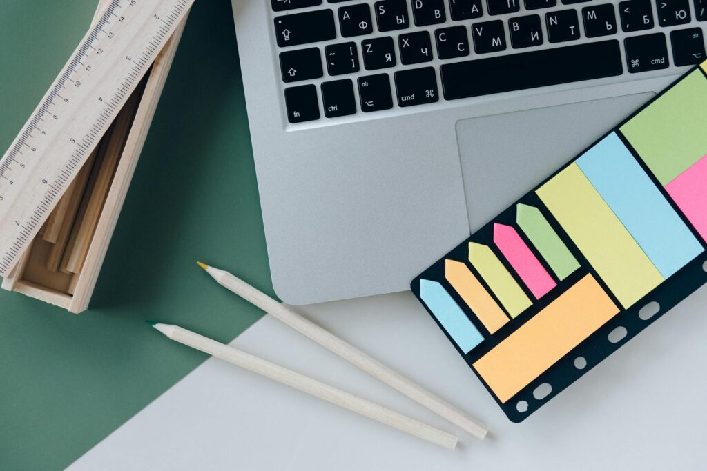 Bureau avec un ordinateur, deux crayons, des notes adhésifs et une règle.